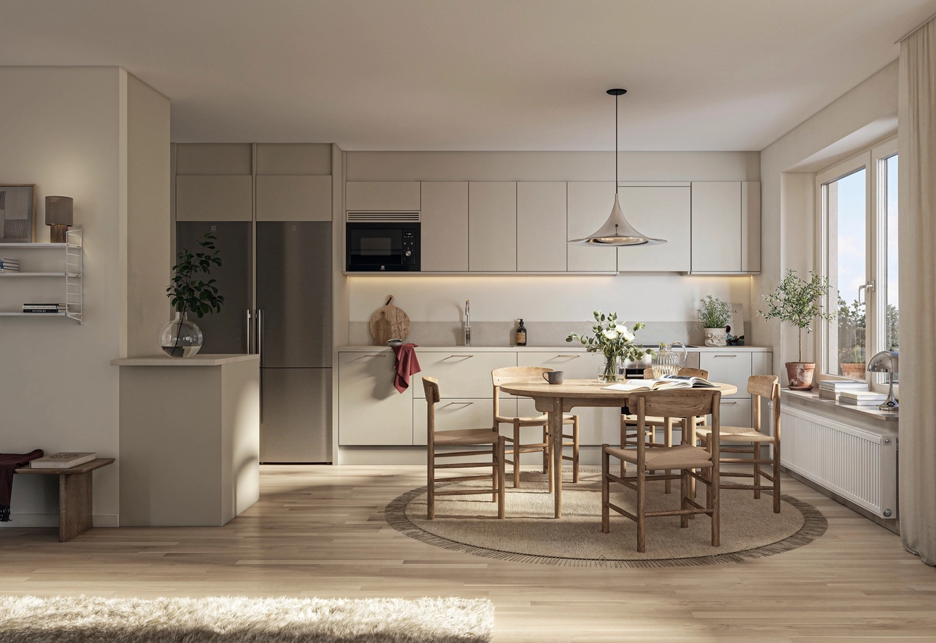 Ljust kök med rostfria vitvaror längs en vägg. Framför står ett runt matbord med fem stolar, precis vid övergången till ett vardagsrum.