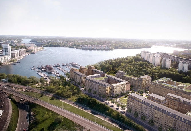 Flygfoto över en stadsstrand med bostadshus, vägar, träd och båtar förtöjda längs strandlinjen.