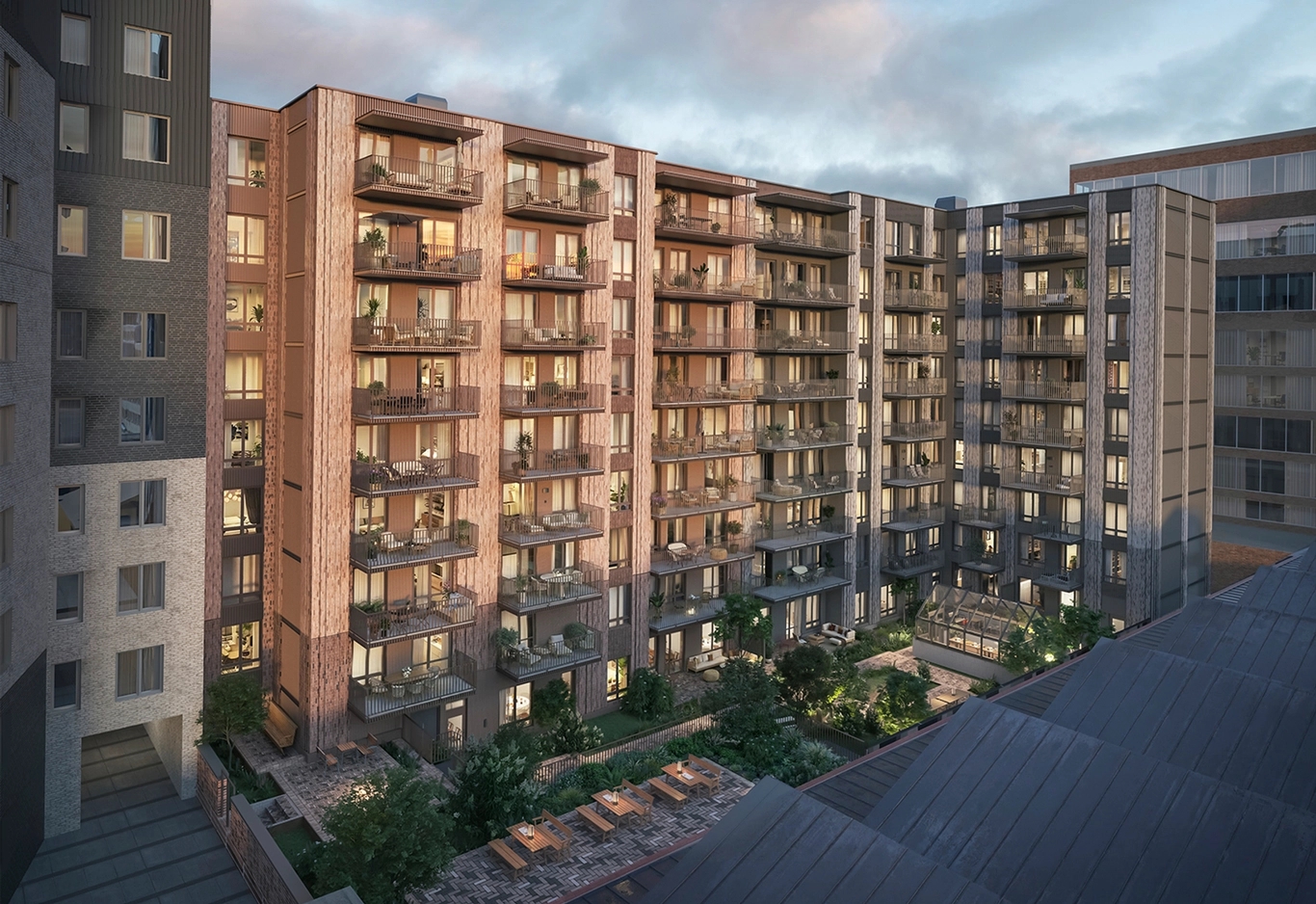 Gårdbild från en flerfamiljshus. Växthus, balkonger och uteplatser. Mycket grönska.