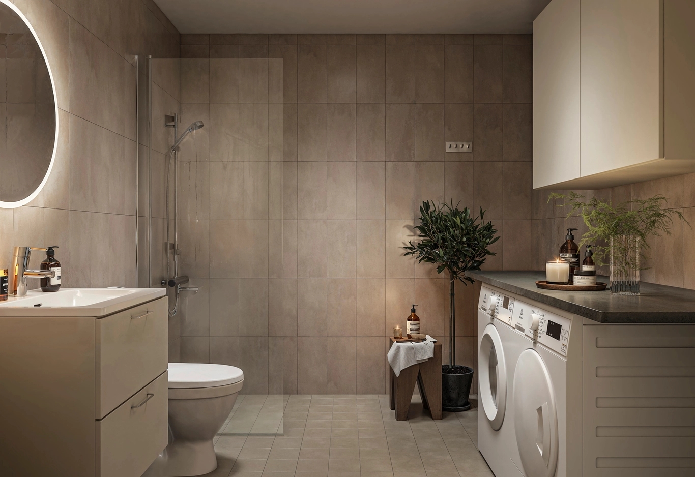 Helkaklat badrum med dämpad belysning och tända ljus. I förgrunden syns en kommod och tvättmaskin och torktumlare.