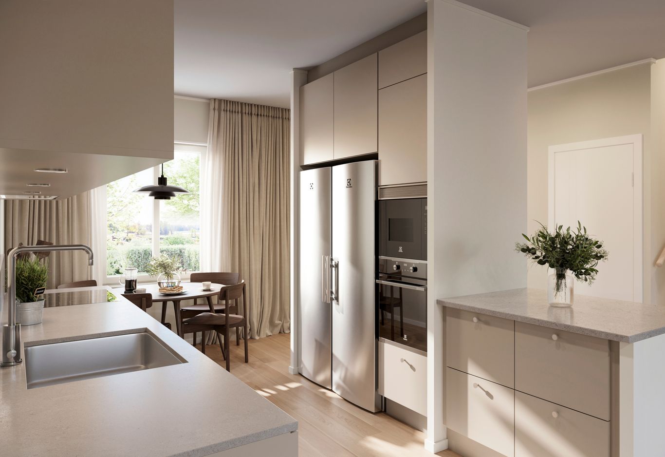 Kök med rostfria vitvaror, sandfärgade skåp och en central köksö med diskho. Ett matbord vid ett fönster med gardiner syns i bakgrunden.