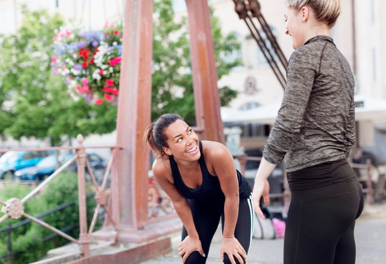 Två kvinnor i pratar och ler i ett utegym.