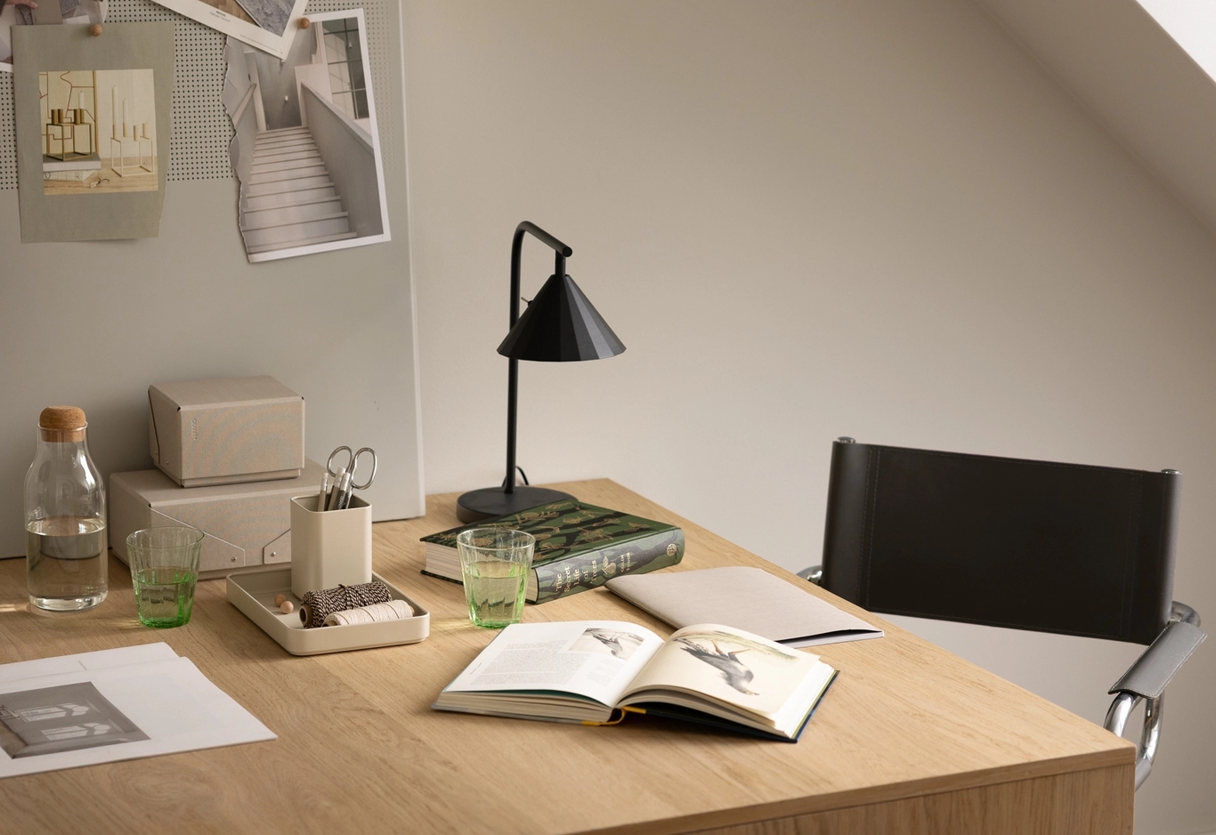 Minimalistisk arbetsplats med penna, papper, skrivbordslampa och andra detaljer.