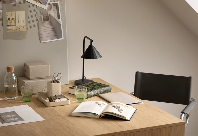 Minimalistisk arbetsplats med penna, papper, skrivbordslampa och andra detaljer.