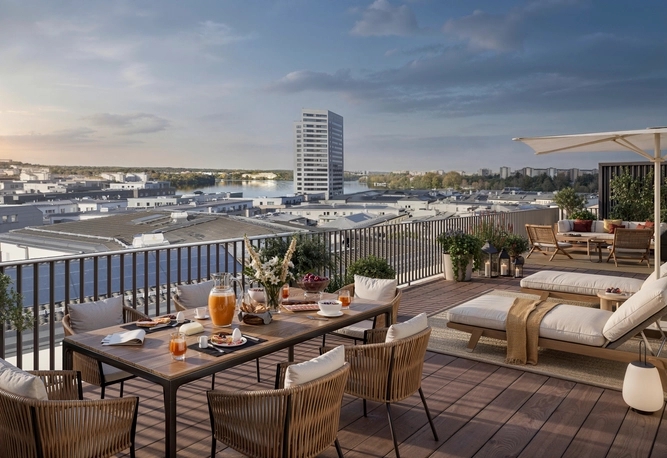 En takterrass med matbord, loungefåtöljer och utsikt över stadsbilden under en klar himmel.