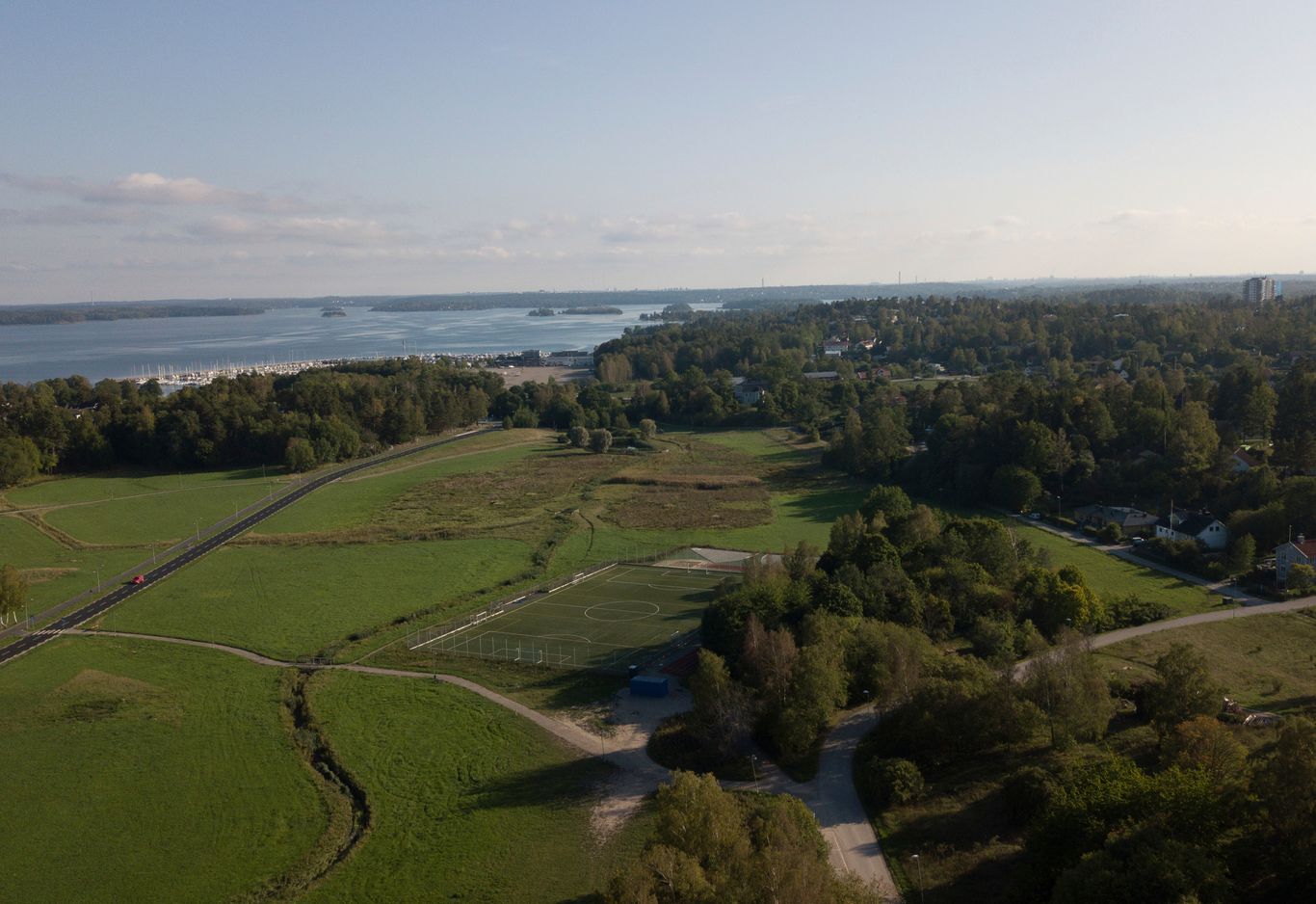 Flygfotografi över ett vidsträckt grönt fält med ett vattendrag i bakgrunden 