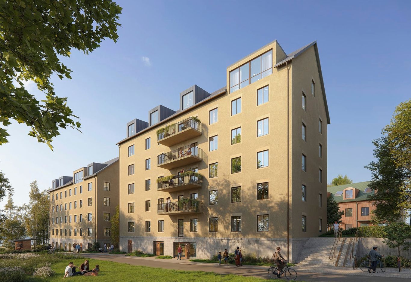 Fem våningar beige flerbostadshus med balkonger omgivet av grönska och träd, under en klarblå himmel. Folk sitter på gräset i förgrunden.